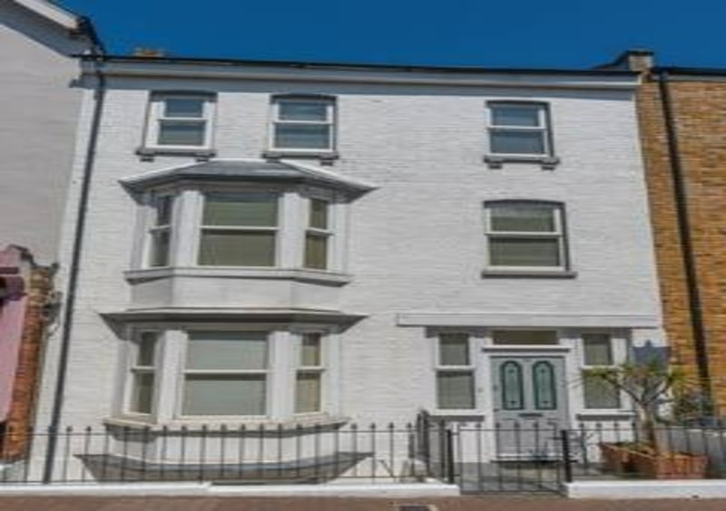 White rendered Victorian terraced house with bay windows and metal railings