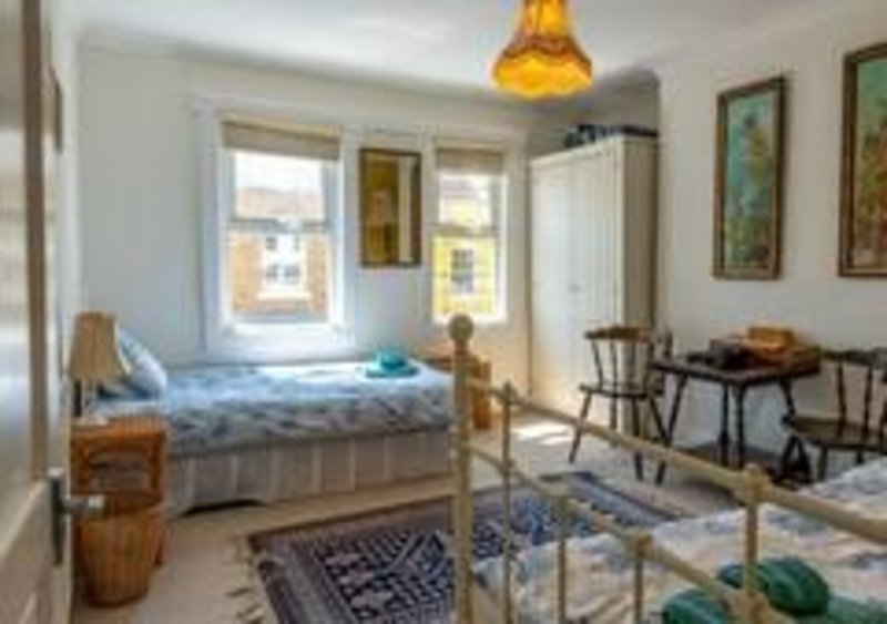 Bright bedroom with two beds, wooden furniture, dining table and framed wall art