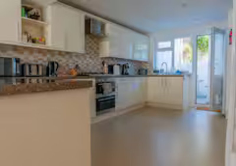 Modern kitchen with white cabinets, geometric backsplash, oven, and open-plan layout with garden access