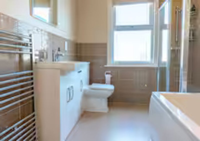 Modern bathroom with white vanity, toilet, heated towel rail and shower enclosure