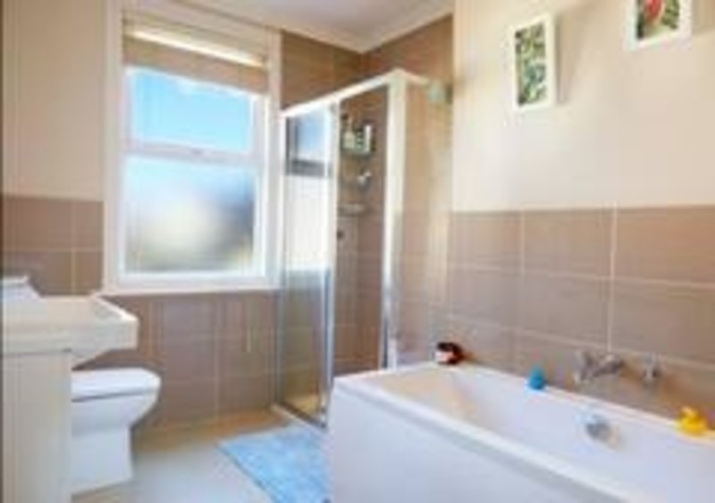 Modern bathroom with white toilet, bathtub, shower enclosure and window