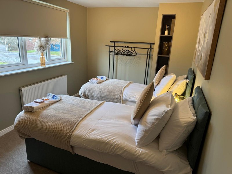 Bright bedroom with two single beds, white bedding, yellow walls, window with blind and radiator