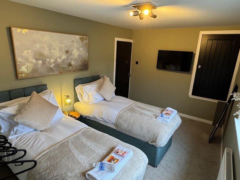 Twin bedroom with two single beds, neutral walls, wall-mounted TV, and ceiling light
