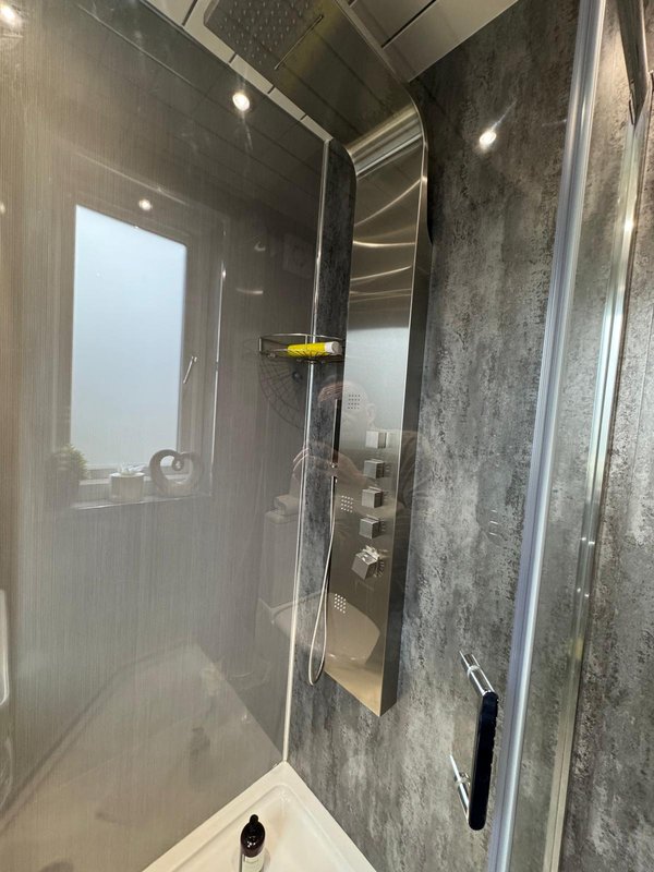 Modern bathroom shower enclosure with glass door and grey tile walls