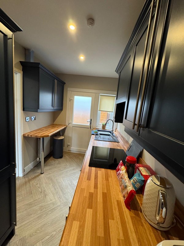 Modern kitchen with black cabinetry, wooden countertops, and stainless steel appliances