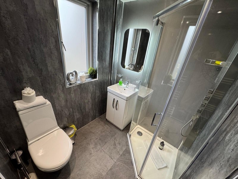 Modern bathroom with toilet, sink vanity, shower enclosure and window