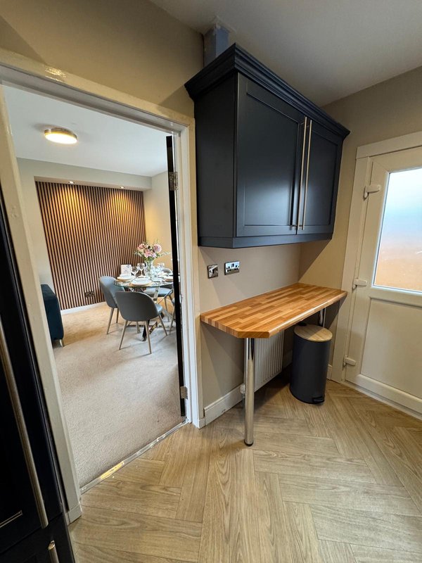 Hallway with desk workspace, black wall cabinet, and open doorway to dining area