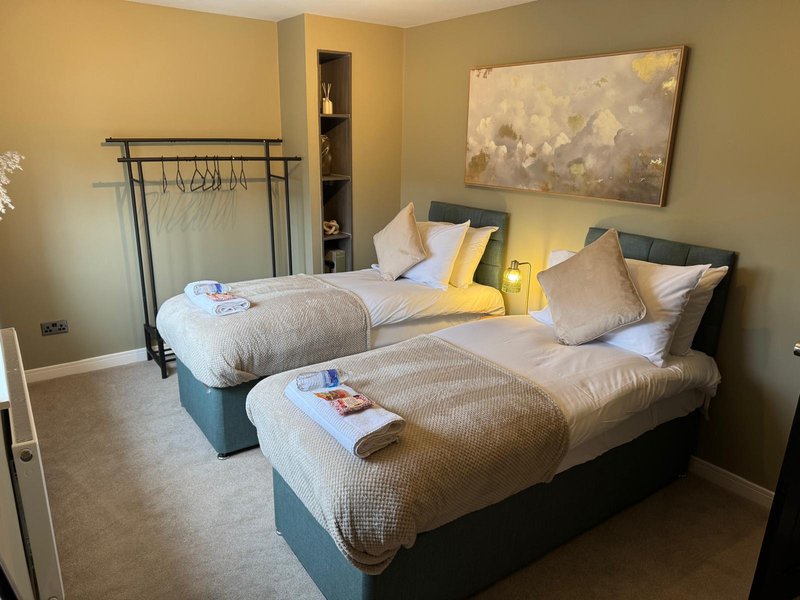 Twin bedroom with two beds, yellow accent pillows, wall art, and built-in shelving