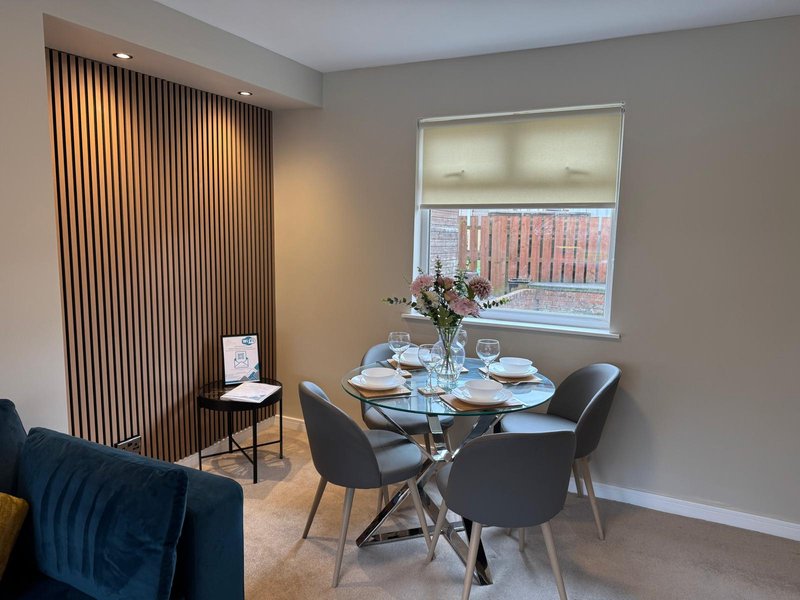 Modern dining area with round glass table, black chairs, window view and contemporary decor