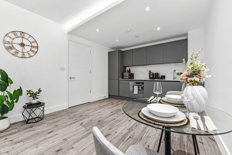 Modern open-plan kitchen and dining area with grey cabinetry, round dining table, and wood-effect flooring