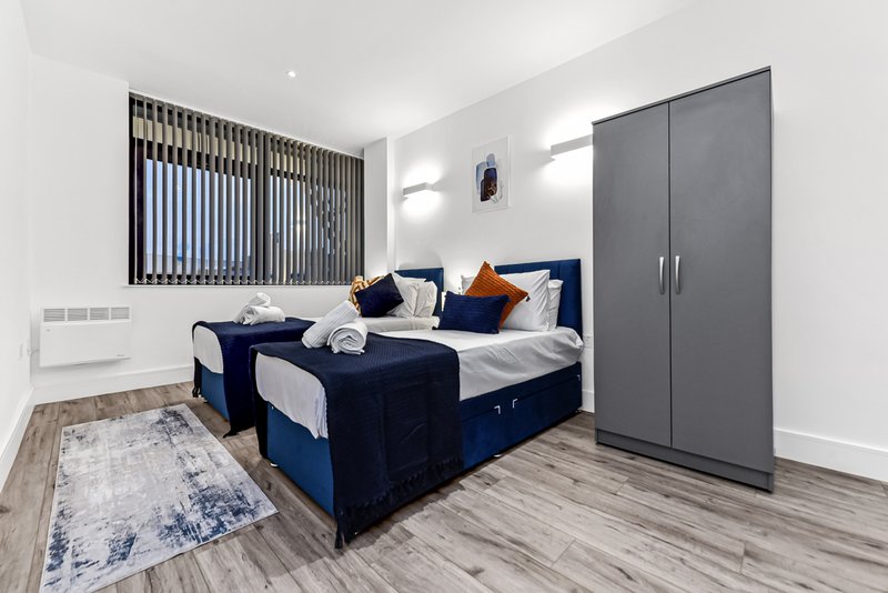 Modern bedroom with twin beds, navy upholstery, gray wardrobe and window blinds