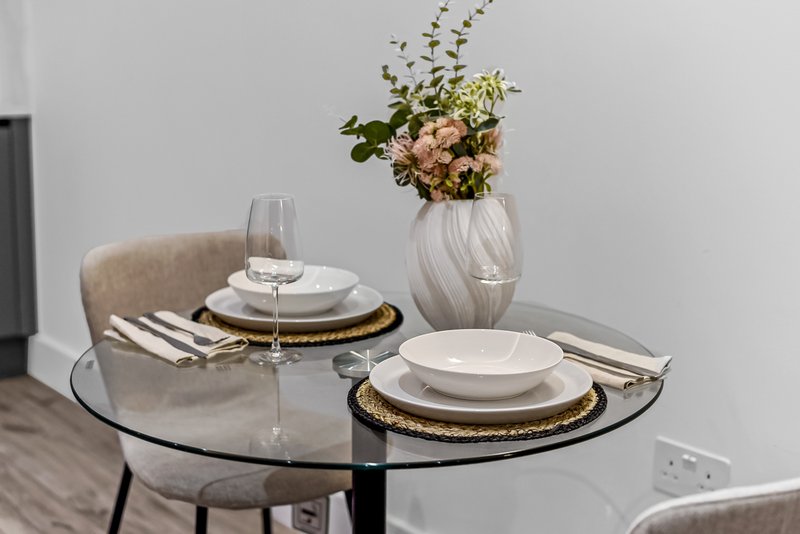 Styled round dining table with place settings, glasses, and floral centerpiece