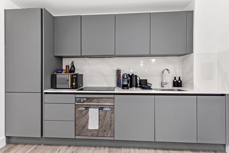 Modern gray kitchen with fitted cabinets, white countertop, stainless steel sink and integrated oven