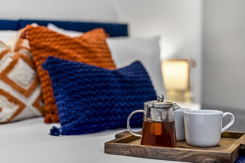 Bedroom detail with teapot, mug, cushions and bed headboard in background
