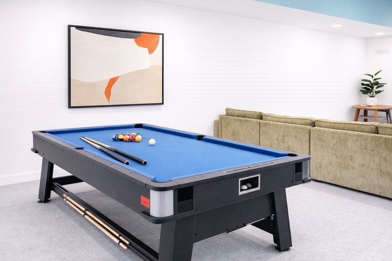 Recreation room with pool table, framed abstract artwork, sofa and potted plant