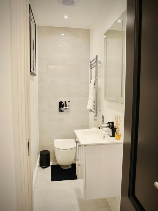 Modern bathroom with white sink, toilet, towel rail and shower enclosure