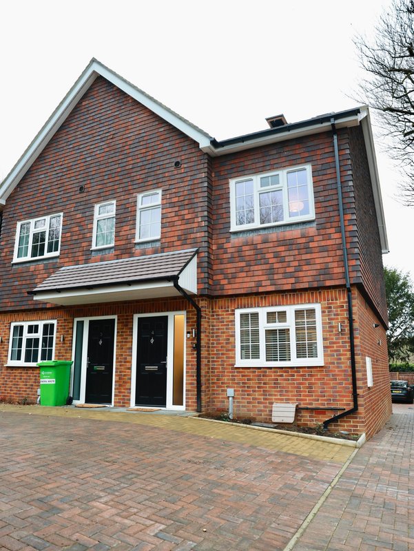 Brick semi-detached house exterior with driveway, garage doors, and front garden