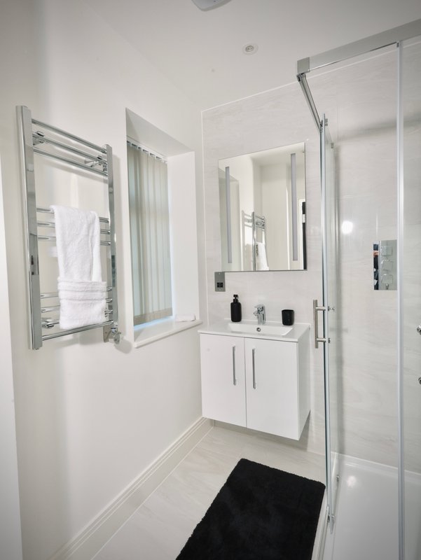 Modern bathroom with white vanity, mirror, towel rail and glass shower enclosure