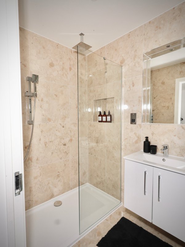 Modern bathroom with walk-in shower, white vanity, large mirror and beige tile walls