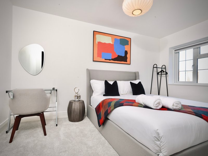 Modern bedroom with double bed, black pillows, colorful wall art, and contemporary furnishings
