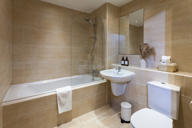 Modern bathroom with bathtub, pedestal sink, toilet, and shower enclosure