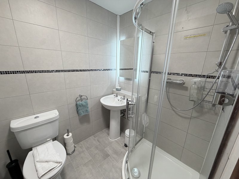 Modern bathroom with shower enclosure, pedestal sink, toilet and tiled walls
