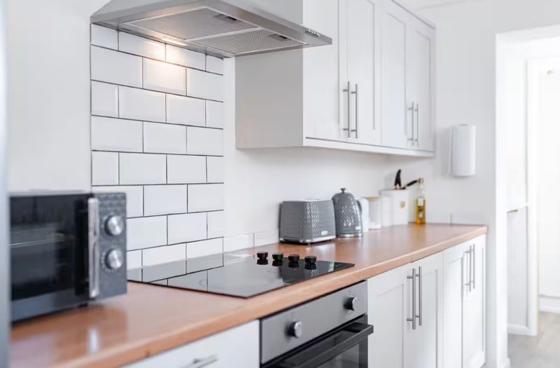 Modern kitchen with white cabinetry, wooden countertop, subway tile backsplash and stainless steel appliances