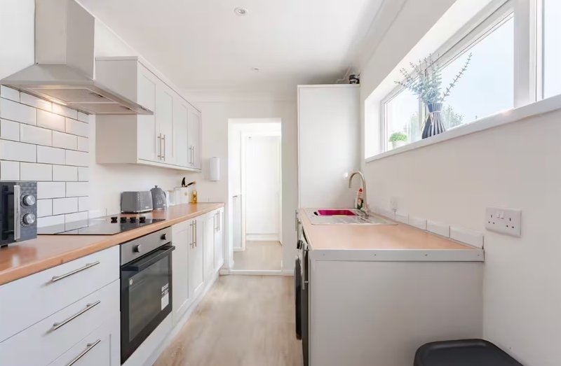 Modern kitchen with white cabinets, wooden countertops, stainless steel appliances and subway tile backsplash