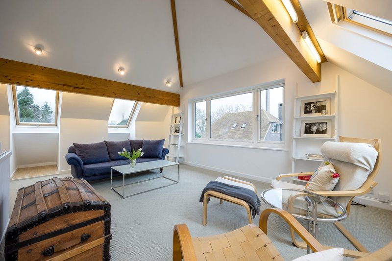Modern loft living room with exposed beams, blue sofa, armchairs and large windows