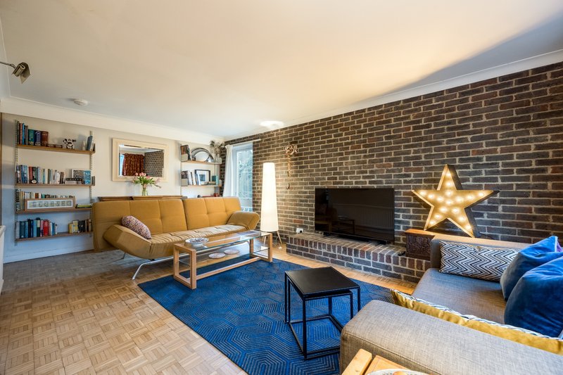 Spacious living room with yellow sofa, exposed brick wall, blue armchair and gold star decoration