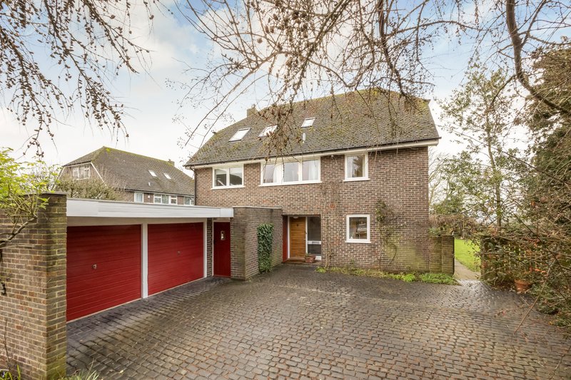 Brick detached house with red double garage, driveway and front entrance