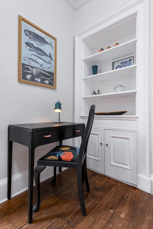 Home office nook with black desk, chair, built-in shelving and framed fish artwork