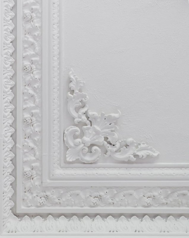 Ornate white decorative ceiling or wall molding with scrolled corner detail