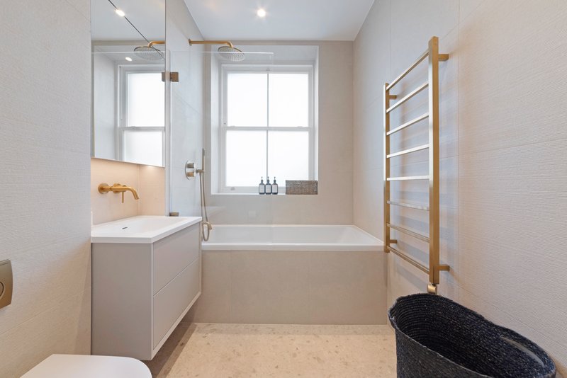 Modern bathroom with white vanity, bathtub, wooden towel ladder and natural light