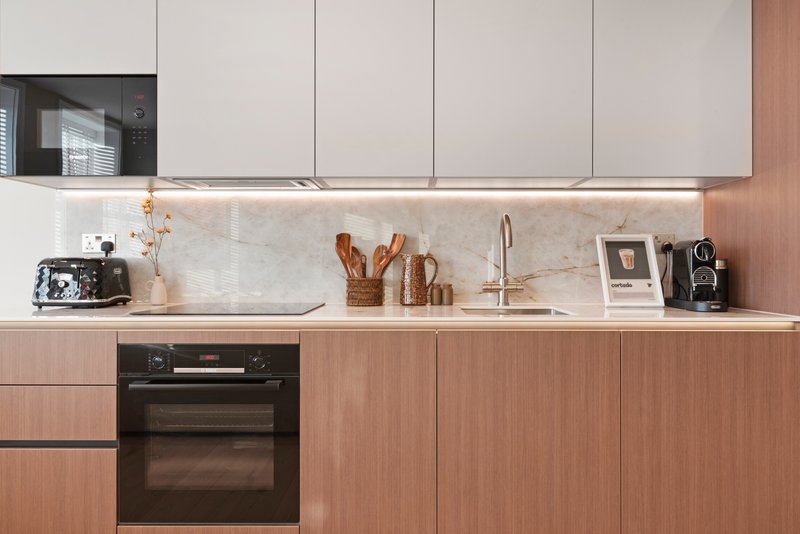 Modern kitchen with terracotta and white cabinetry, marble backsplash, built-in oven and countertop appliances