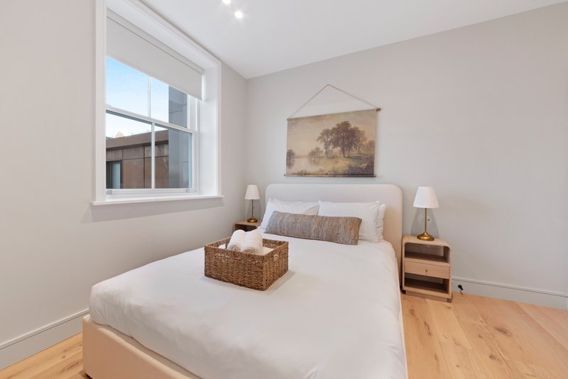 Bright bedroom with double bed, wicker storage basket, wooden nightstands and window