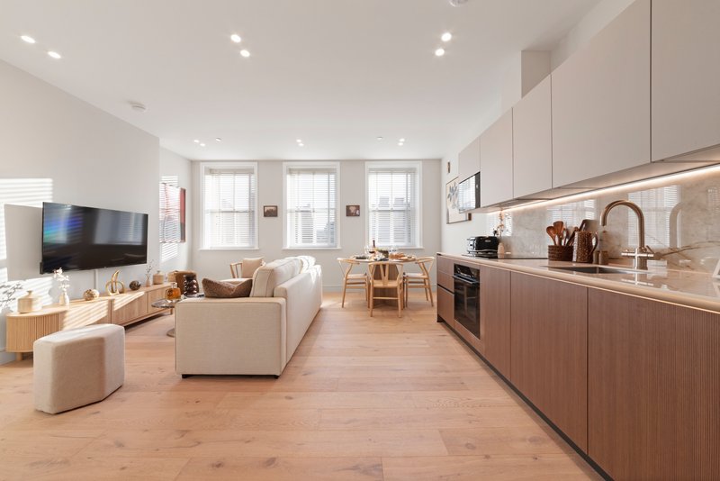 Open-plan living and kitchen area with cream sofa, wooden flooring and modern cabinetry