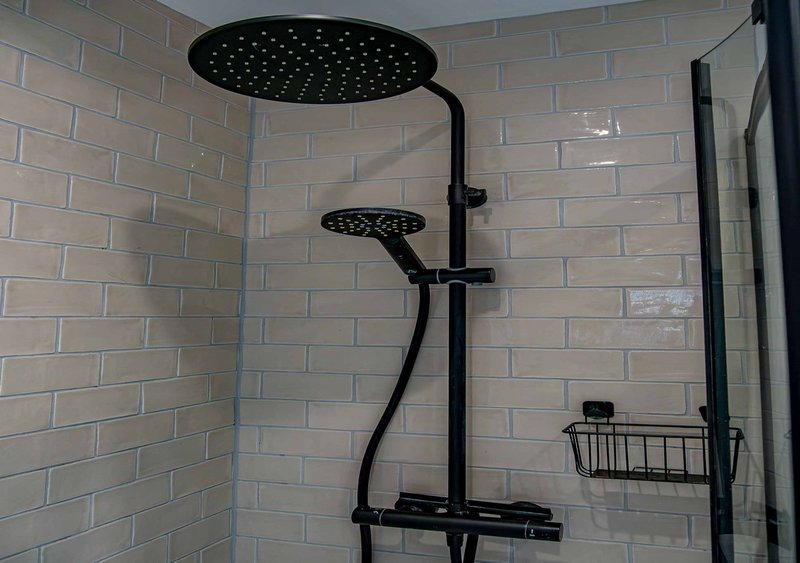 Modern bathroom shower with dual rainfall showerheads, black fixtures and white subway tile walls