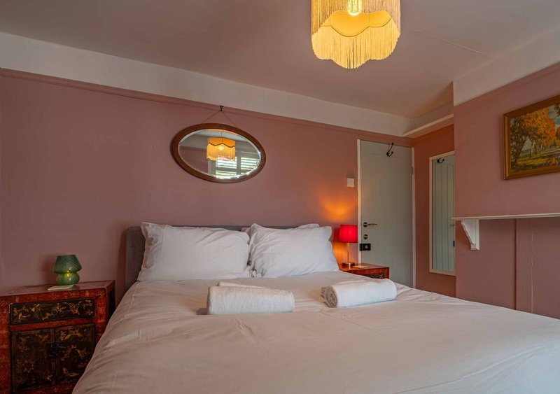 Bedroom with double bed, pink walls, bedside lamps, and ceiling light fixture