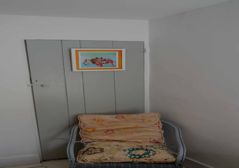 Sparse room corner with metal-framed daybed, patterned cushions, and framed wall art