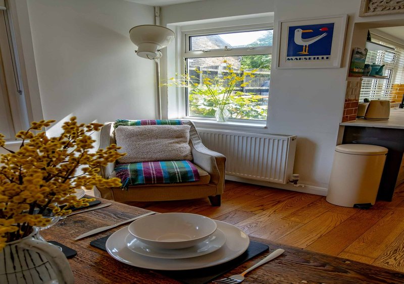 Living room with wooden furniture, colorful cushions, window view, and dining table setup