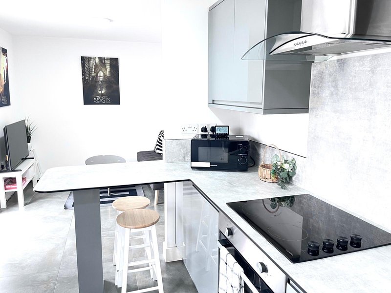 Modern kitchen with white cabinetry, island with seating, gas hob and range hood