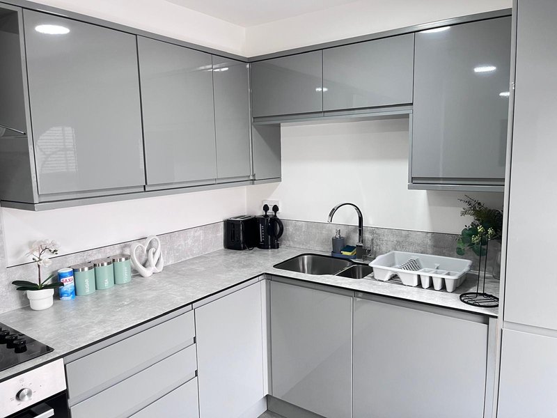 Modern white kitchen with gray cabinets, marble countertop, sink and appliances