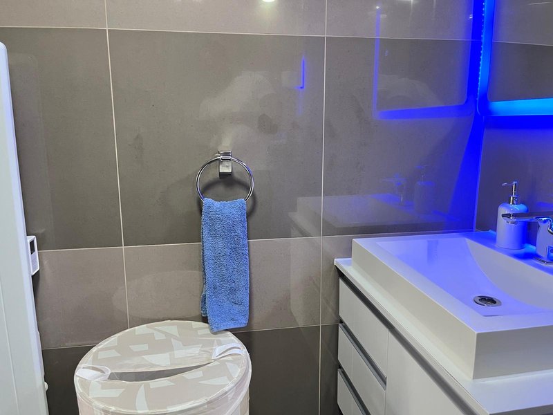 Modern bathroom with toilet, towel rail, white vanity sink and blue accent lighting