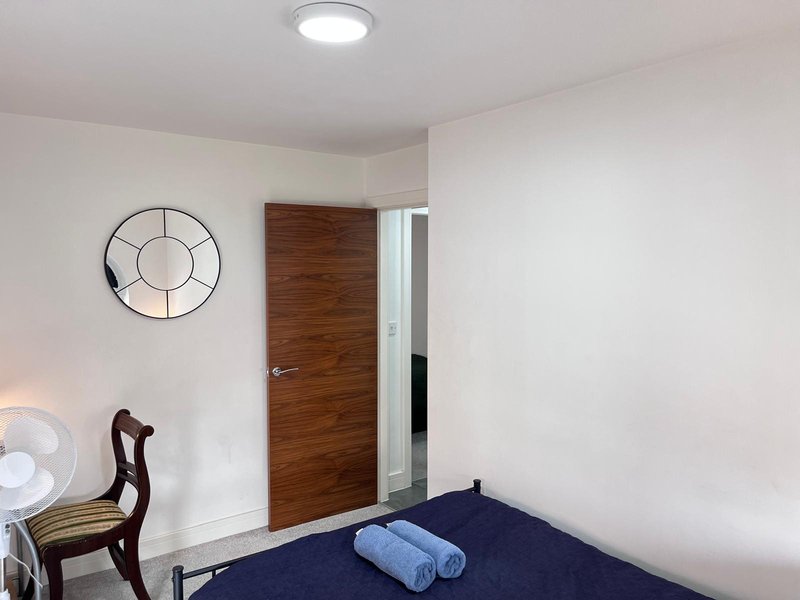 Bedroom with blue bed, wooden door, decorative wall clock and ceiling light