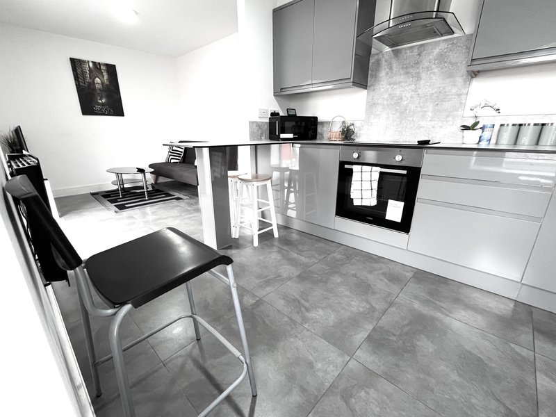 Modern kitchen with white cabinetry, island seating, and open-plan living area