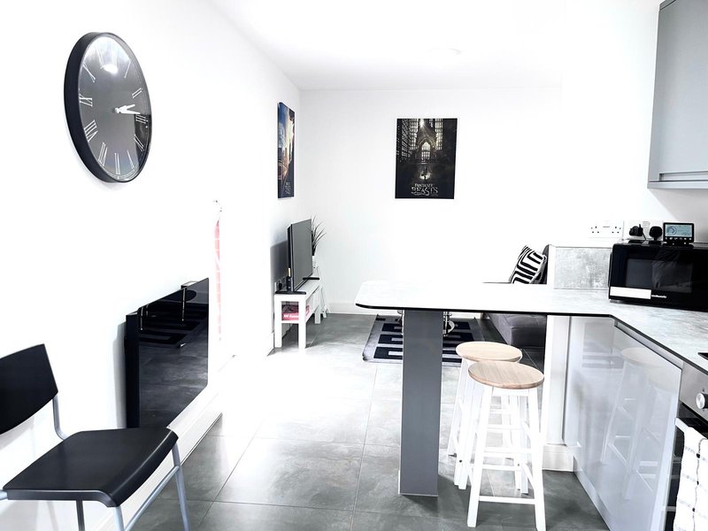 Modern open-plan kitchen and dining area with white cabinetry, grey dining table, and wall clock