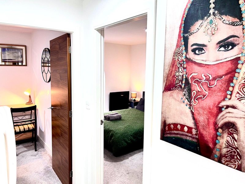 Interior hallway with pink walls, open doorways showing bedrooms, and decorative wall art