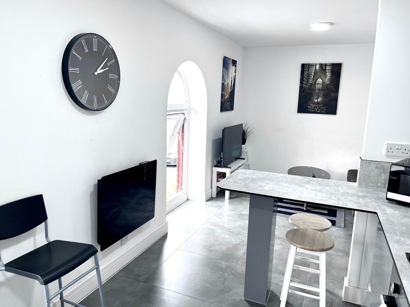 Modern open-plan office space with white walls, marble desk, black chairs and wall clock