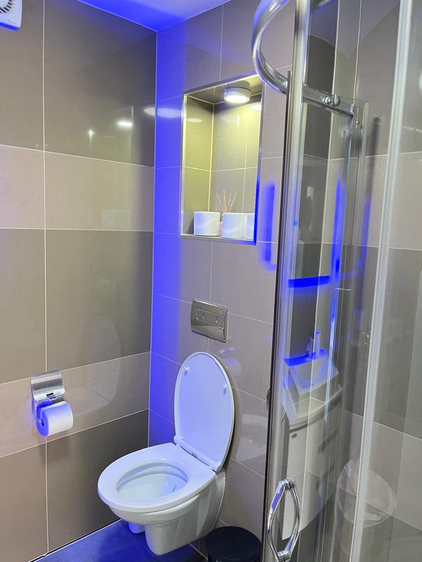 Modern bathroom with toilet, shower enclosure, and blue ambient lighting